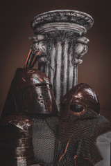 Still life at studio withs belt, ancient pedestal and two helmets.