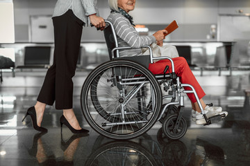 Female worker moving elderly woman in wheelchair boarding