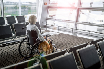 Elderly woman on wheelchair looking on window