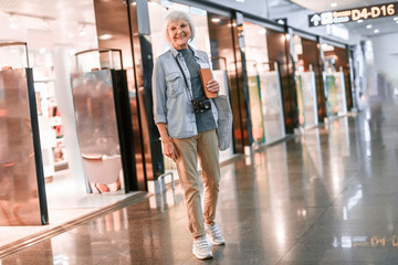 Fototapeta premium Smiling mature female is walking with camera