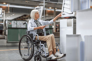 Smiling mature woman on disabled carriage checking in