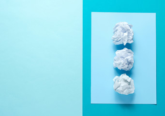 Three crumpled paper balls on a blue background. Minimalistic business concept. Top view
