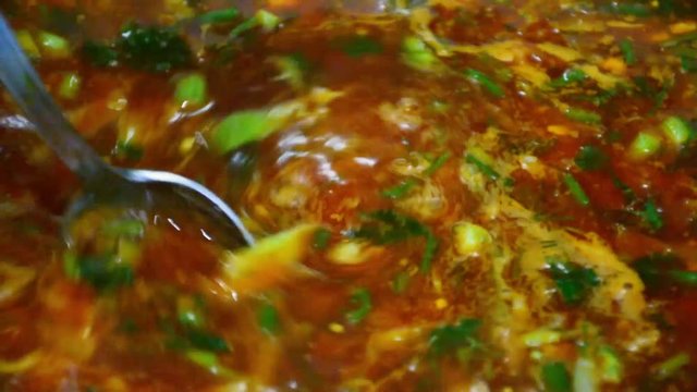 Cooking healthy food. Soup with greens boils on the stove.