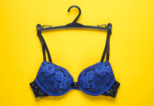 Sexy bra with hanger on yellow background. Top view