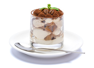 Classic tiramisu dessert in a glass on plate with spoon isolated on a white with clipping path