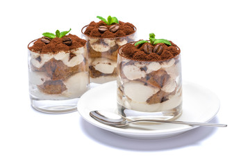 Classic tiramisu dessert in a glass on plate with spoon isolated on a white with clipping path