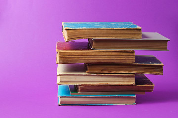 Stack of old books on purple background.