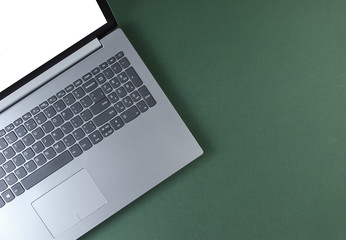 Fragment of laptop with a white screen on a green background. Top view - obrazy, fototapety, plakaty