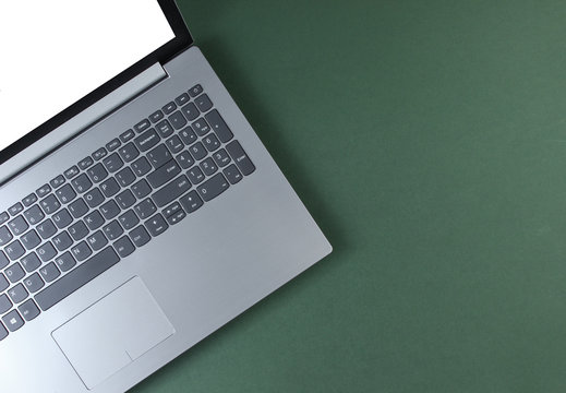 Fragment of laptop with a white screen on a green background. Top view