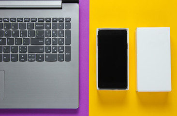 The concept of unboxing, techno blogging. Box with a new smartphone, laptop on yellow purple...