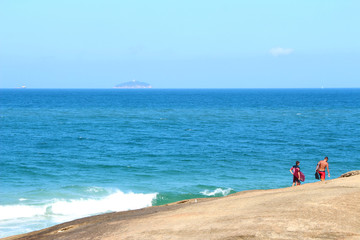 surfers walking on the stone by the sea