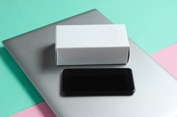 The concept of unboxing, techno blogging. Box with a new smartphone, laptop on pastel background.