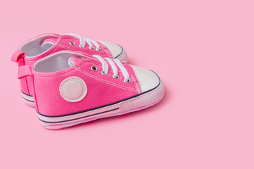 Cute pink baby girl sneakers close up on pink background