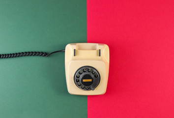 Retro rotary phone on a red-green paper background. Top view