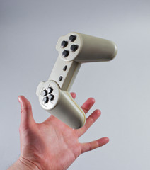 Male hand catches gamepad on a gray background. © splitov27
