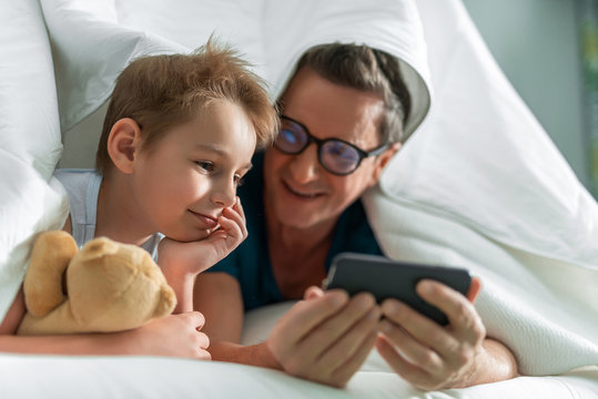 Happy father and son using smartphone in room