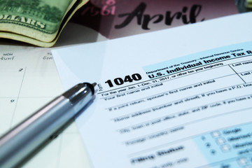 Tax Season: 1040 U.S. Individual Income Tax Return Form Horizontal top right view of an office laptop background with a metallic pen preparation on taxation. - image