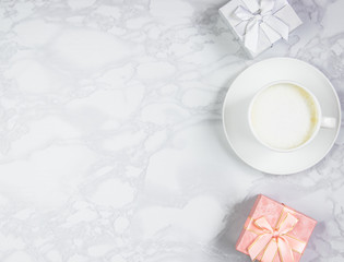 Workplace top with a cup of coffee and gift boxes on a marble table. Top view, flat lay, copy space