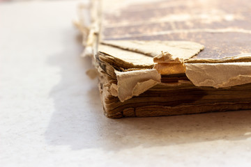 Old book on white surface. Disheveled book. A worn-out book on a white surface. A worn-out book on a white background