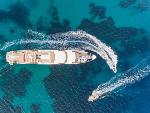 Aerial View Of Jet Ski Driving Around Luxurious Yacht In The Mediterranean Sea, Mikonos Island, Greece.