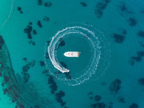 Aerial view of jet ski driving around yacht in the mediterranean sea, Mikonos island, Greece.