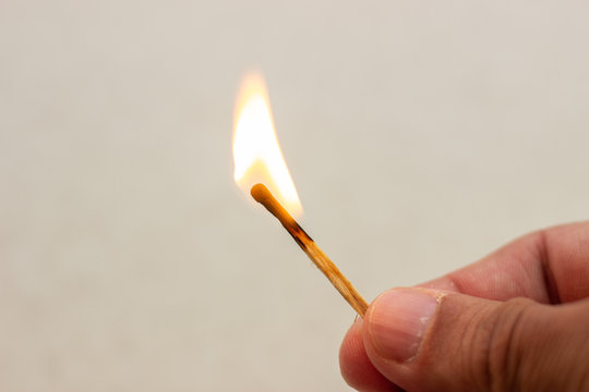 Lit match in hand. A lit match on a white background. Lighted match in hand on white background. Burning match in hand. Burning match on white background
