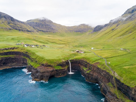 Aerial view faraway of M˙lafossur waterfall near a small village, Faroe island.
