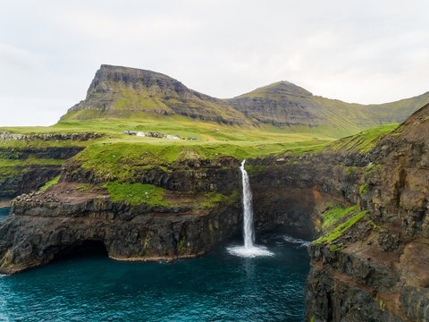 Aerial view faraway of M˙lafossur waterfall near a small village, Faroe island.