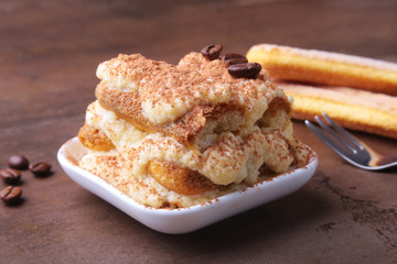 Piece of appetizing homemade tiramisu cake on plate in close up.
