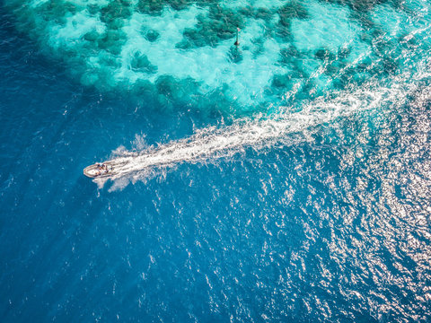 Aerial view of people in a boat in the turquoise sea of Bora-Bora, French Polynesia.