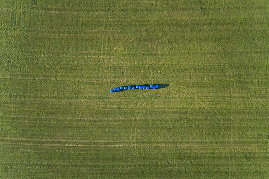 Aerial view of hay envolve in plastic in the middle of agricultural fields.