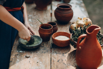 Woman grinds grass with a pestle in a mortar