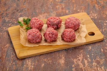 Raw meatball over wooden background