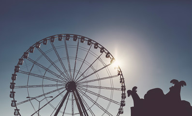 Silhouette of a Ferris wheel at sunset, color toning applied.