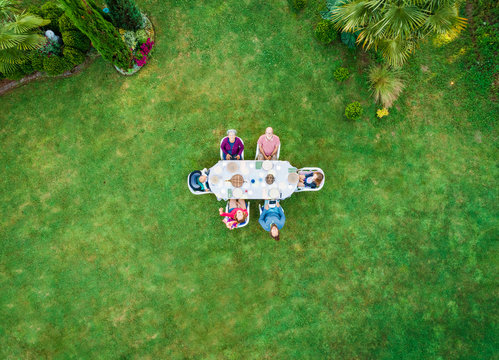 Aerial view of extended family at garden table for lunch.