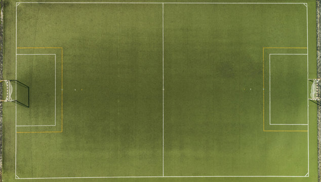 Aerial view of a green synthetic football pitch with white and yellow lines.