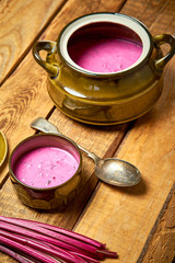 Old vase with  cold beetroot soup and spoon on rustic wooden table