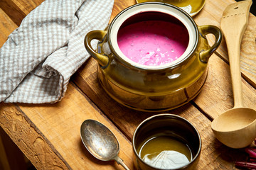 Old vase with  cold beetroot soup and spoon on rustic wooden table