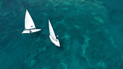 Aerial photo of small sail boat operated by children in exotic tropical bay with turquoise sea