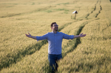 Happy farmer with raised arms in barley field