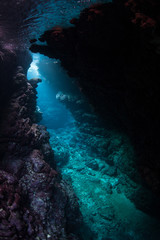 Fototapeta na wymiar Light descends into the darkness of a submerged cavern in the Solomon Islands. Caves and caverns riddle coral reefs since limestone can be easily eroded.