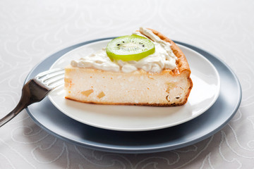 Homemade cottage cheese cake with kiwi fruit and cream on a plate