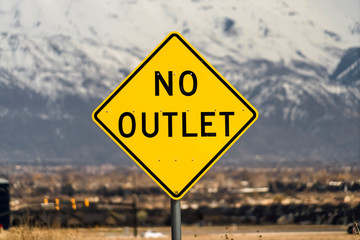 Close up view of a bright yellow and black No Outlet road sign