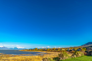 Fototapeta premium Panoramic view of a lake and snow covered mountain under deep blue sky