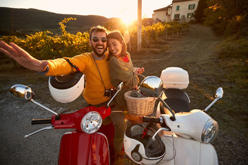 Man and woman on romantic road trip on scooter at sunset on vacation..