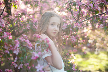 teen girl near the blossoming apple trees in sun rays