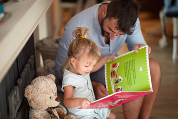 Father with child looking picture book - Powered by Adobe
