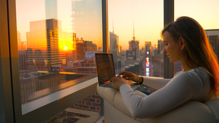 CLOSE UP: Businesswoman living in downtown NYC typing a report at sunrise.