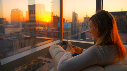 CLOSE UP: Girl looks at her smartphone from her office overlooking Times Square.