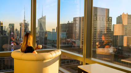 COPY SPACE: Girl enjoying the view of New York in morning with a cup of coffee.
